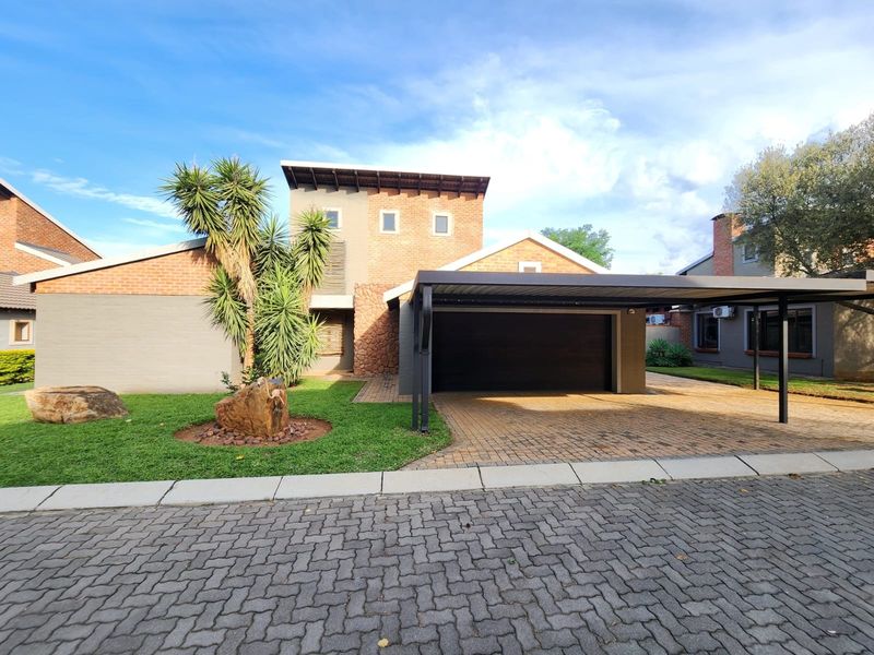 Front elevation of a modern house featuring a brick and stone facade, a paved driveway, and a covered carport.