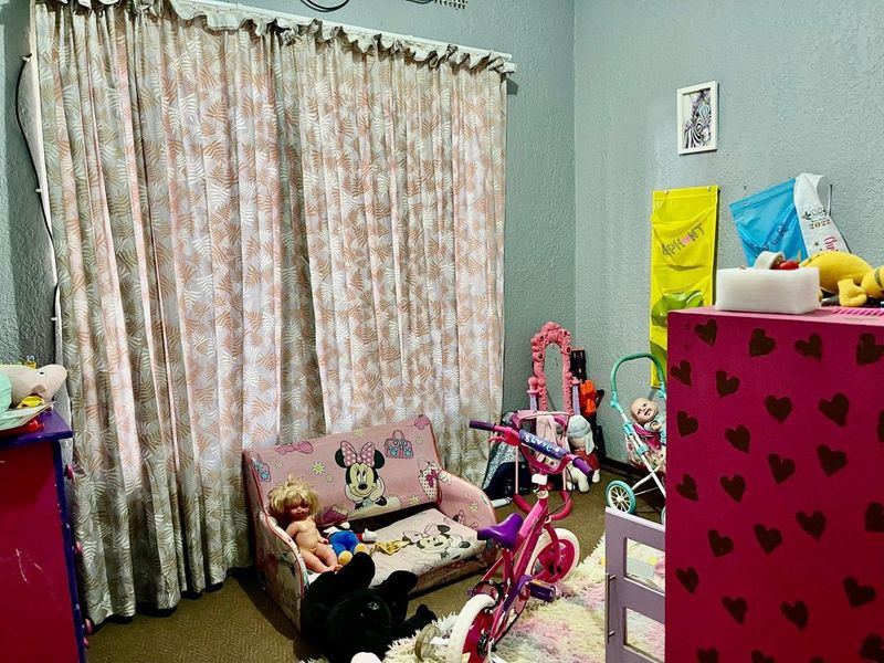 A bedroom featuring textured walls and a full-length curtain rail, currently utilized as a children's play area.
