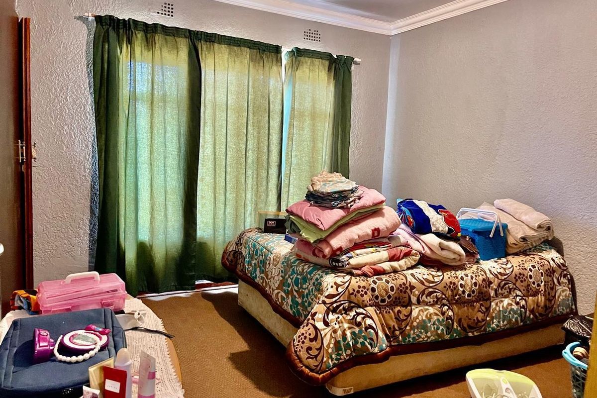 A bedroom featuring crown molding and window treatments, providing a functional space with potential for cosmetic updates.