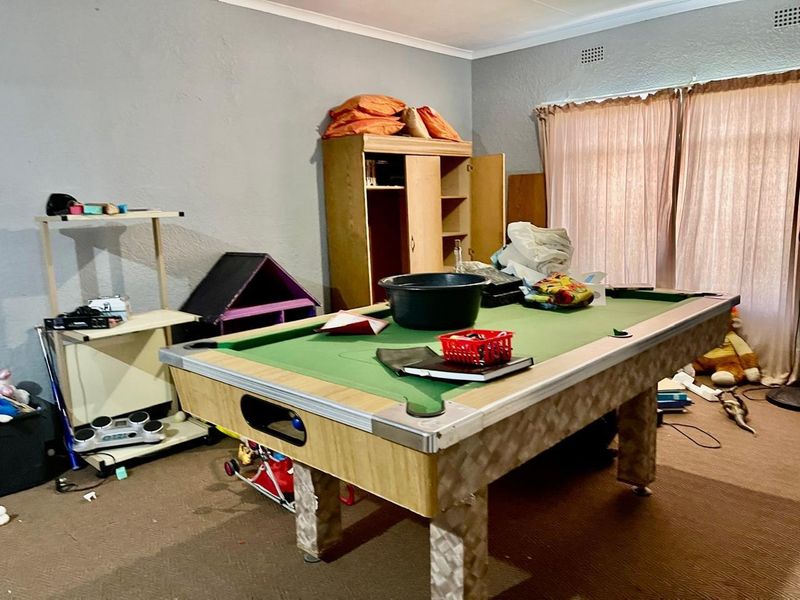 A living area featuring carpeted flooring, cove cornicing, and a ventilation grille, currently utilized as a recreational space.