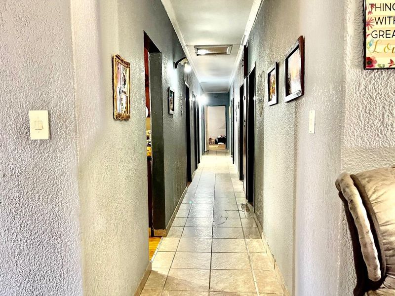 A long residential hallway featuring tiled flooring and multiple access points to adjacent rooms, providing a central circulation path through the home.
