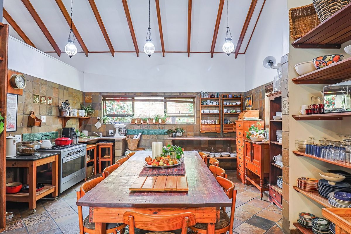 Spacious rustic-style kitchen featuring exposed timber beams, slate tile finishes, and ample built-in shelving, creating a warm and functional culinary space.