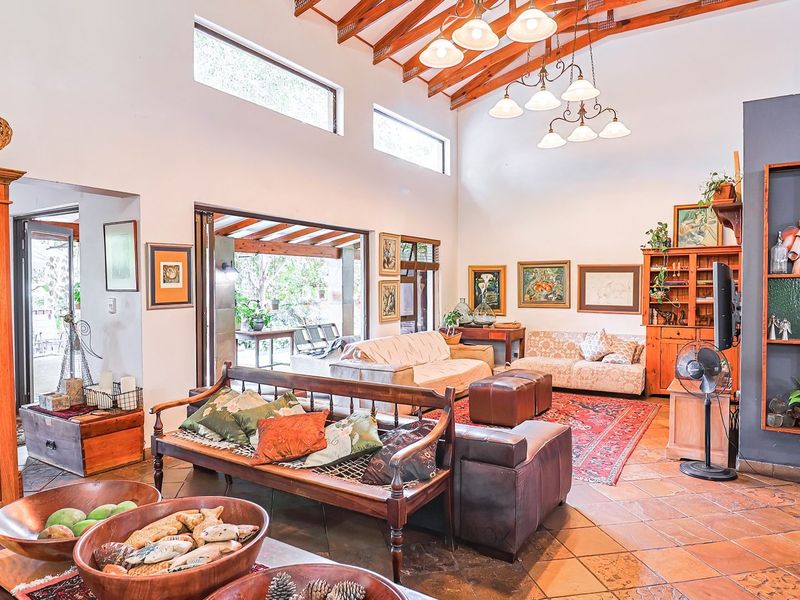 Spacious living room featuring high vaulted ceilings with exposed timber rafters, terracotta tiled flooring, and large clerestory windows providing ample natural light.