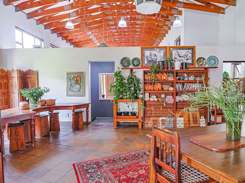Spacious living area featuring high vaulted ceilings with exposed timber trusses, stone tile flooring, and a warm, open-plan layout.