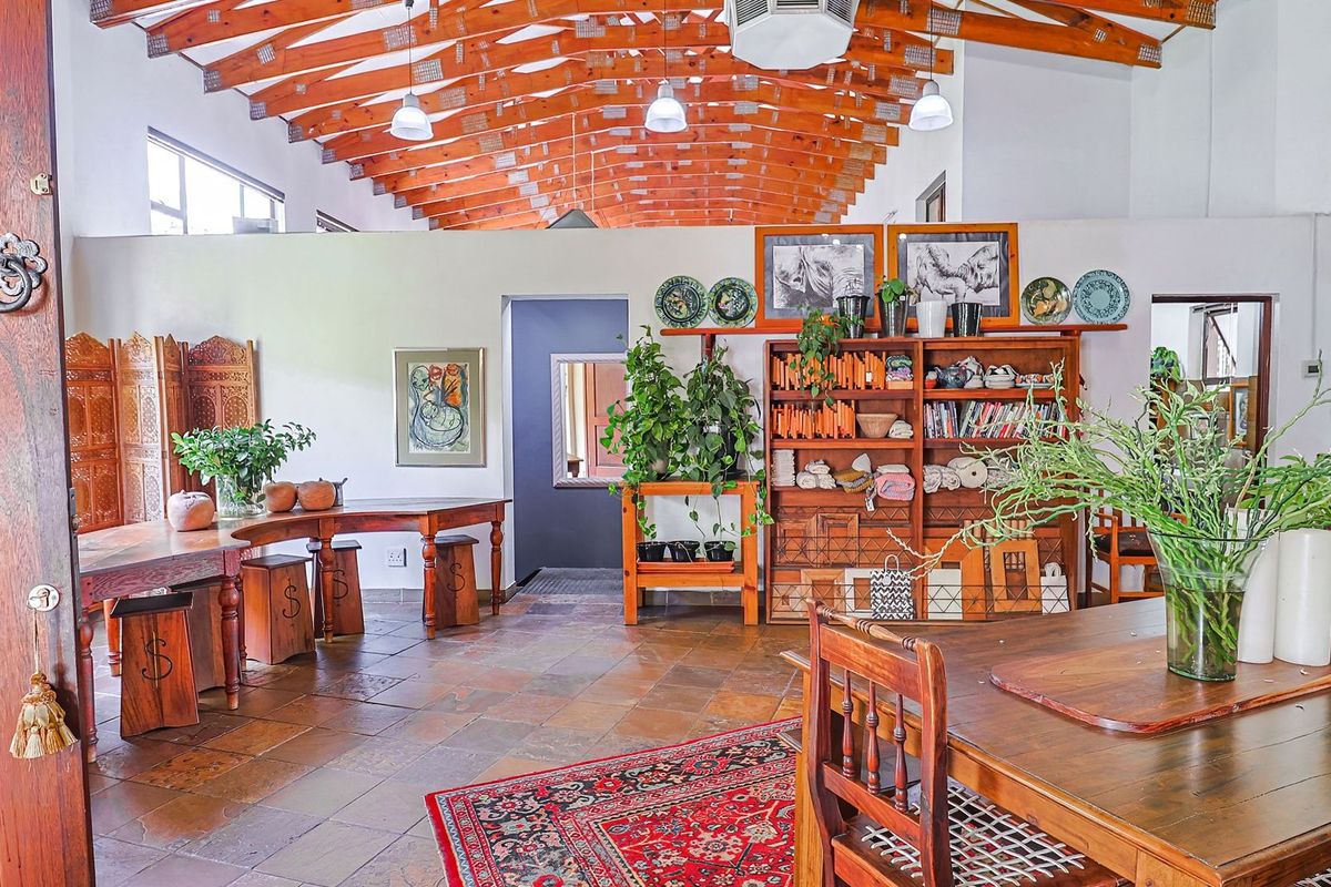 Spacious living area featuring high vaulted ceilings with exposed timber trusses, stone tile flooring, and a warm, open-plan layout.