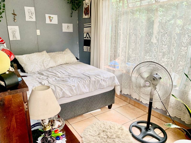 A bedroom featuring tiled flooring and a large window allowing natural light into the space.