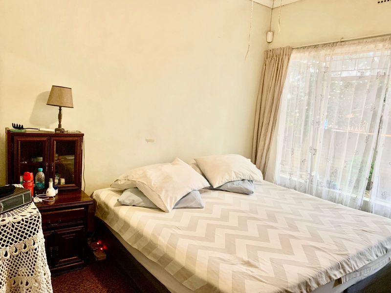 A bedroom featuring a window with curtain rails and visible wear on the wall surfaces.