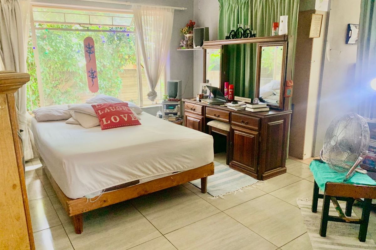 A bedroom featuring tiled flooring and a large window allowing natural light into the space.