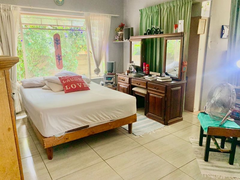 A bedroom featuring tiled flooring and a large window allowing natural light into the space.