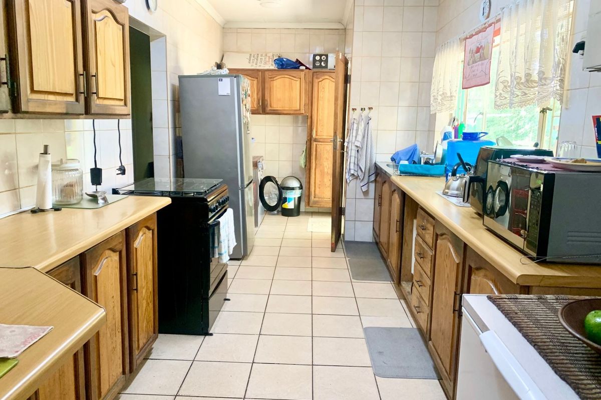 A functional kitchen featuring wooden cabinetry, laminate countertops, and tiled flooring, offering a traditional layout with ample storage and workspace.
