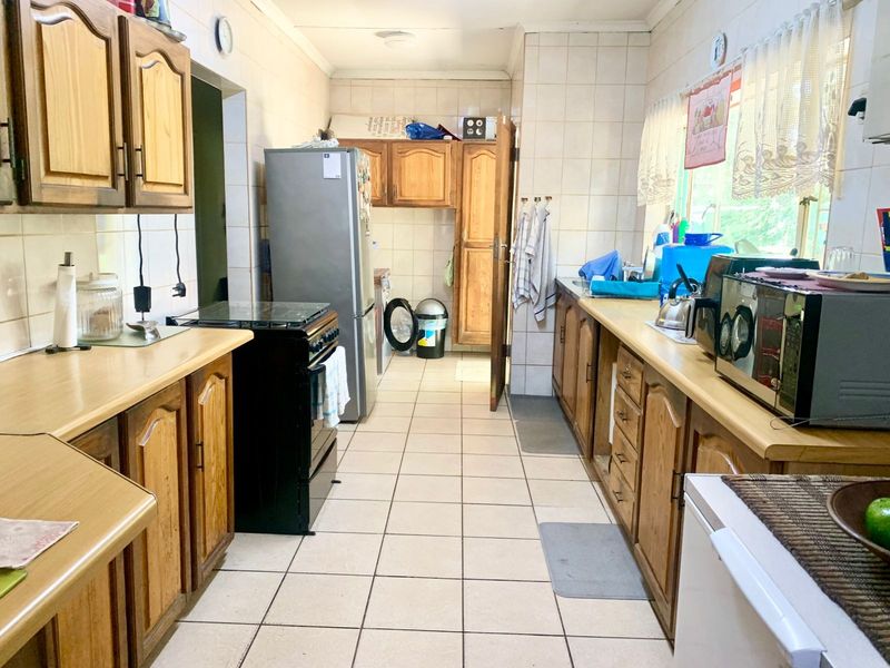A functional kitchen featuring wooden cabinetry, laminate countertops, and tiled flooring, offering a traditional layout with ample storage and workspace.