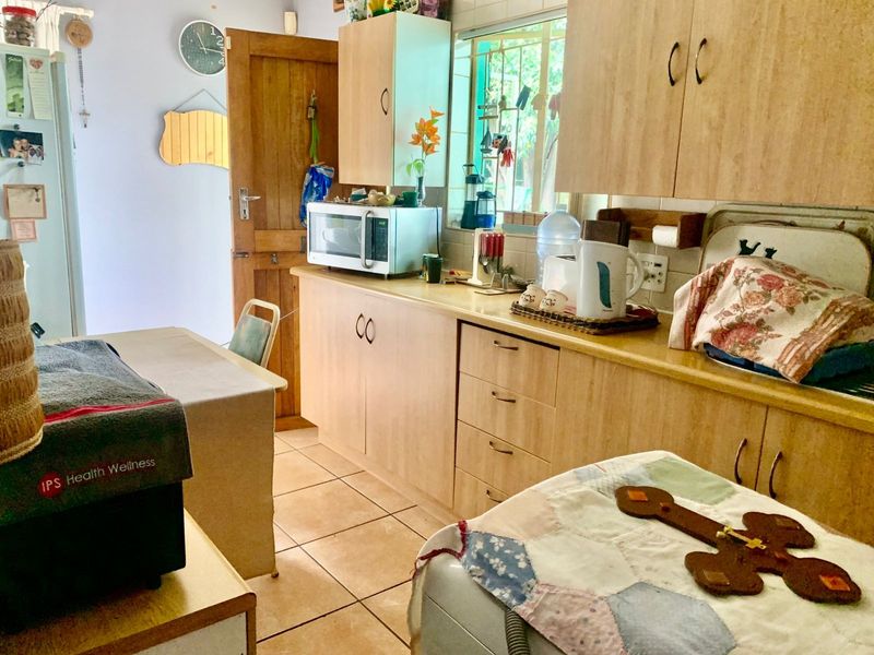 A functional kitchen featuring laminate cabinetry, tiled flooring, and a window with security bars, providing a practical workspace.