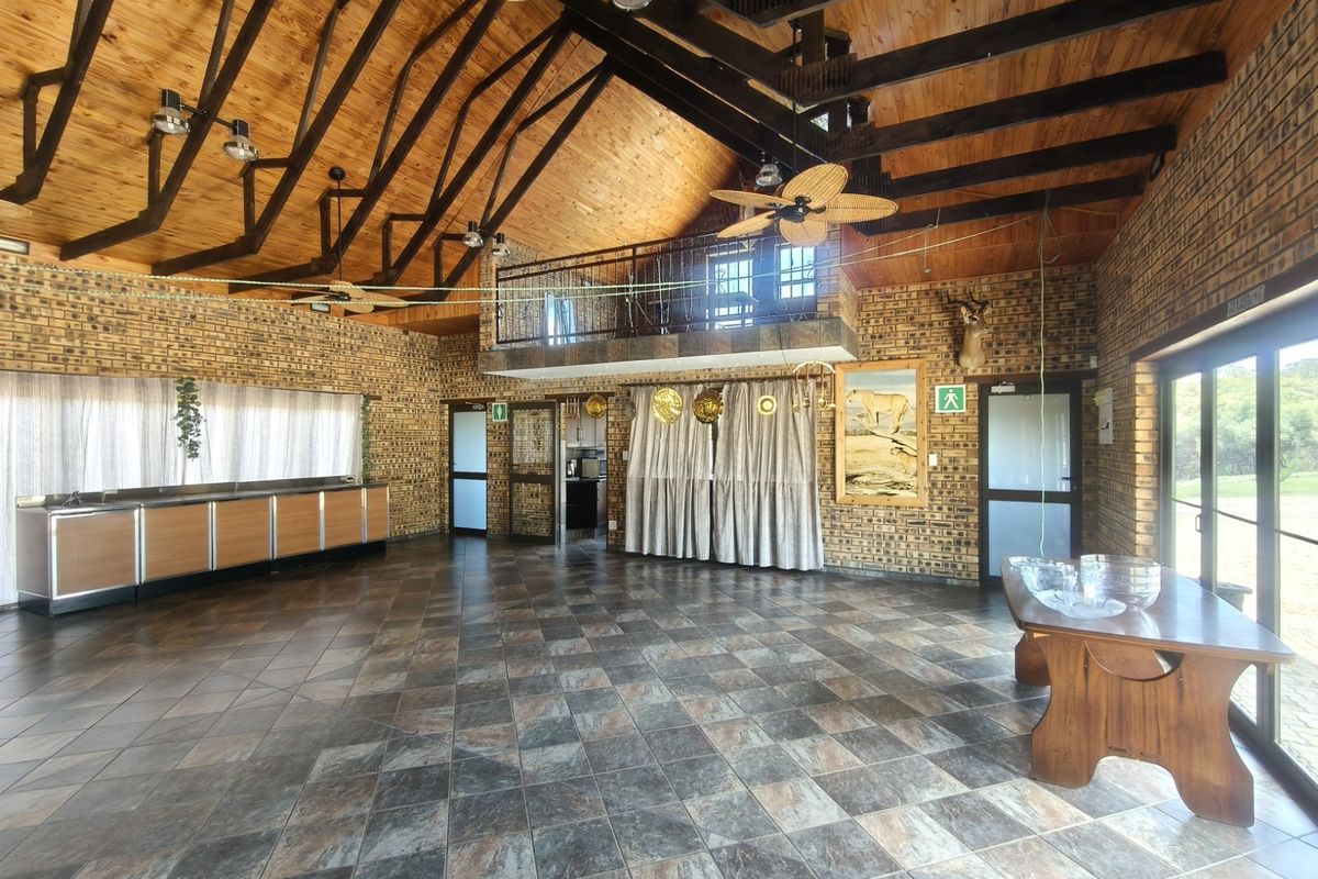 Spacious living area featuring high vaulted timber ceilings, exposed rafters, facebrick walls, and a mezzanine level with a metal balustrade.
