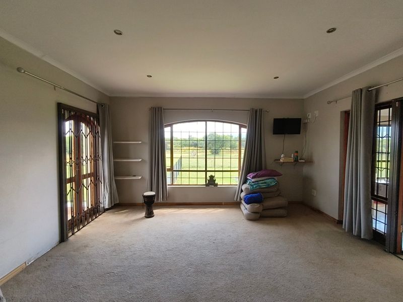 Spacious living room featuring an arched window with garden views, recessed lighting, and carpeted flooring, offering a bright and versatile living space.