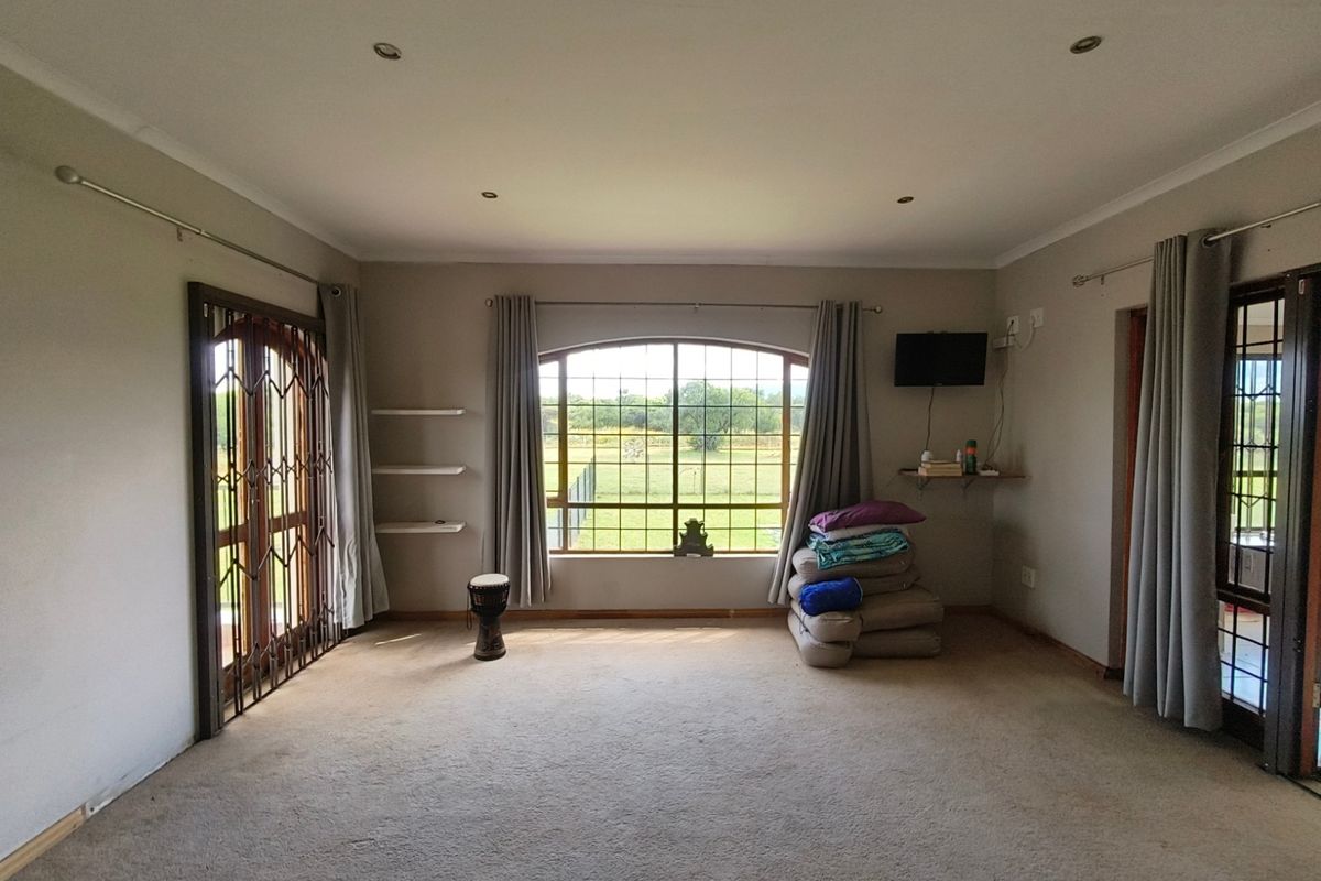 Spacious living room featuring an arched window with garden views, recessed lighting, and carpeted flooring, offering a bright and versatile living space.