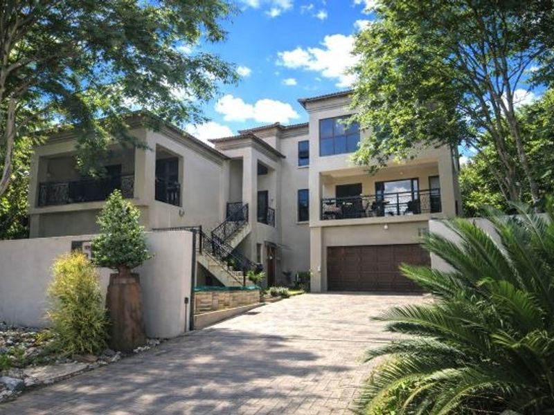 A multi-story residential property featuring a paved driveway, double garage, and multiple covered balconies with wrought iron railings.