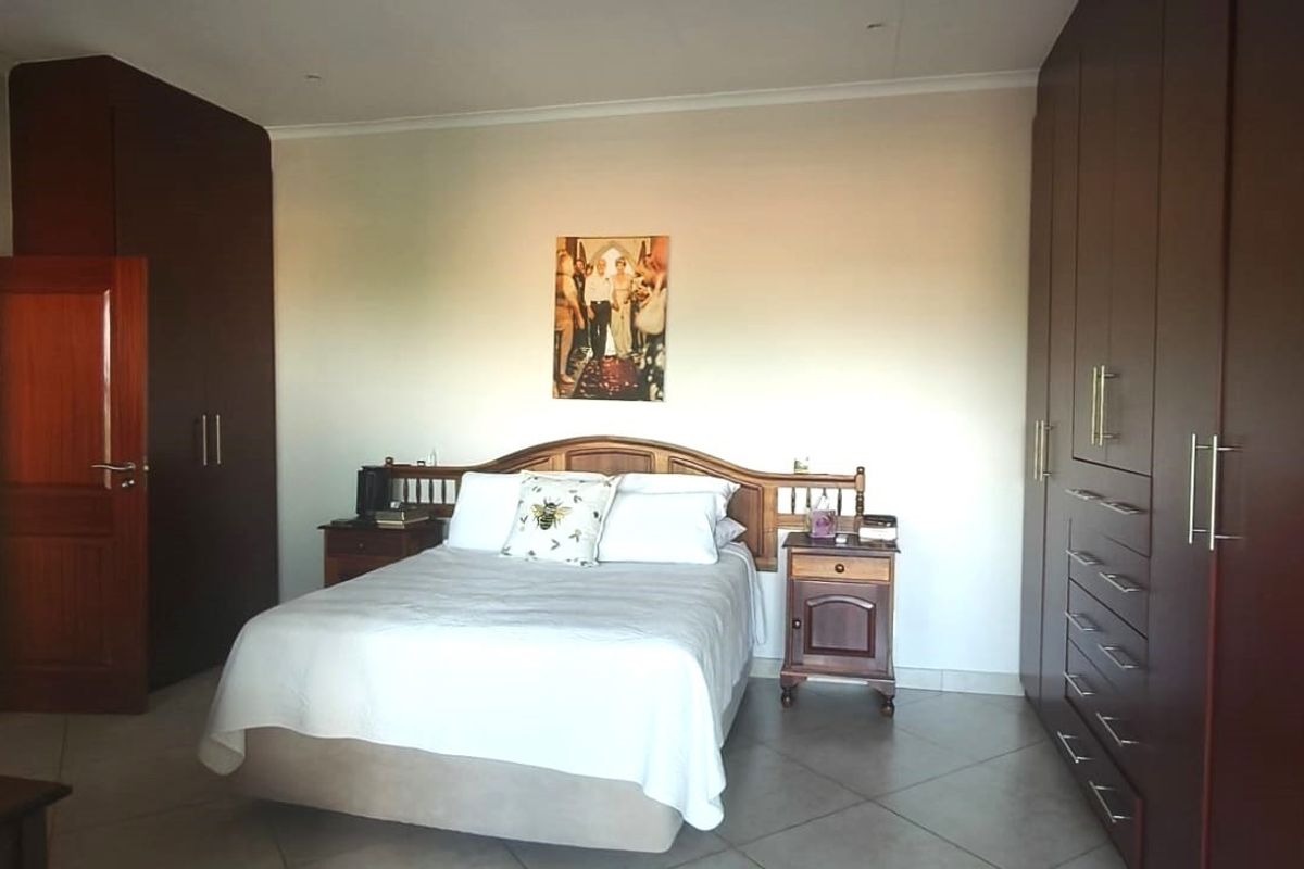 Spacious bedroom featuring extensive dark wood built-in cabinetry and neutral tiled flooring, offering ample storage and a functional layout.