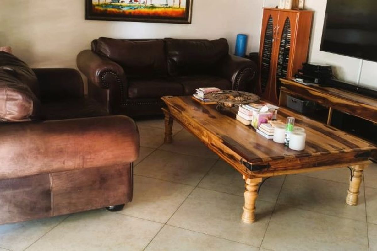 A living room featuring neutral tiled flooring and venetian blinds, providing a functional and comfortable space for relaxation.