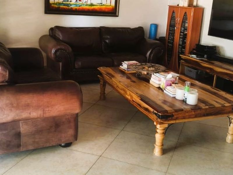 A living room featuring neutral tiled flooring and venetian blinds, providing a functional and comfortable space for relaxation.