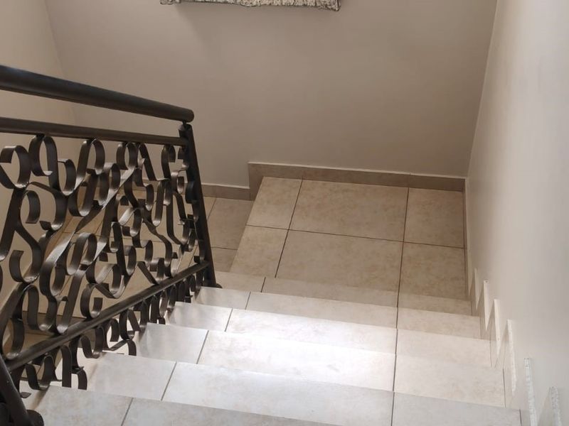 A tiled staircase featuring a decorative wrought iron balustrade, providing a clean and functional transition between levels.