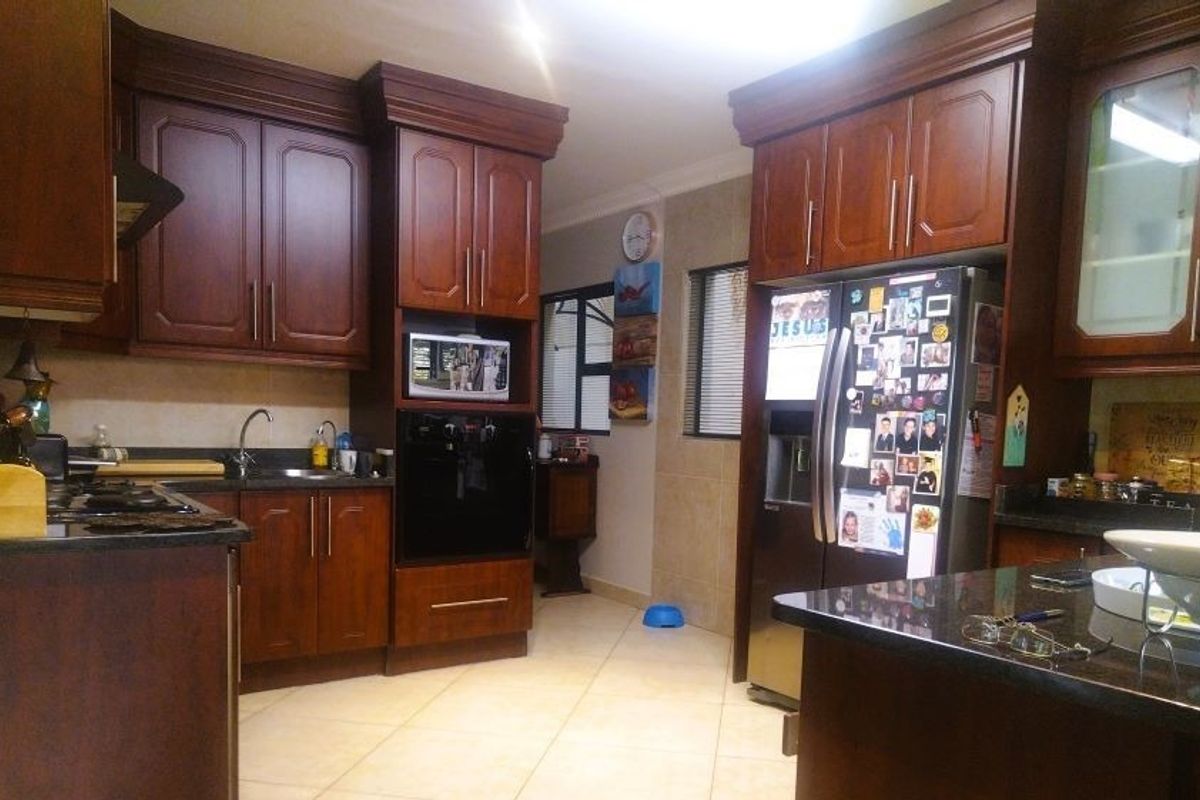A functional kitchen featuring dark wood cabinetry, granite countertops, and built-in appliances, offering a classic aesthetic with ample storage space.