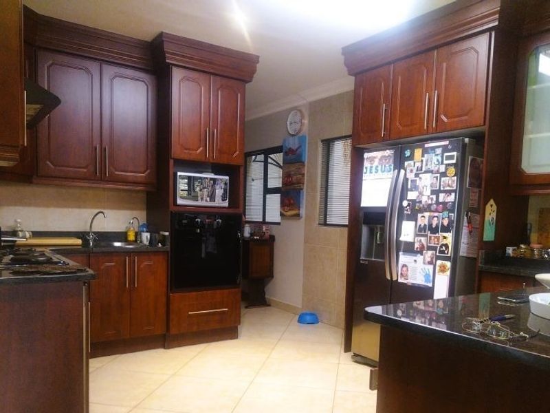 A functional kitchen featuring dark wood cabinetry, granite countertops, and built-in appliances, offering a classic aesthetic with ample storage space.