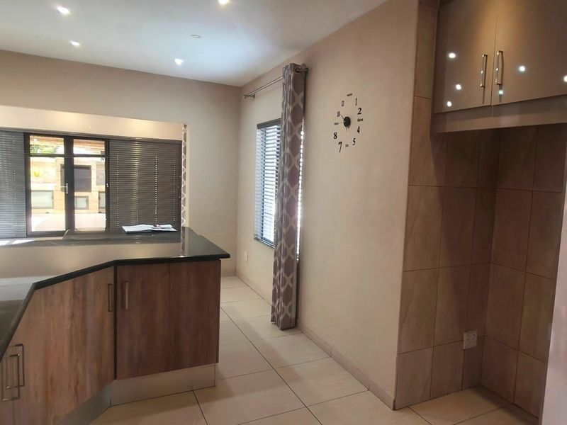A modern kitchen featuring wood-finish cabinetry, granite countertops, and tiled flooring, offering a clean and functional space.