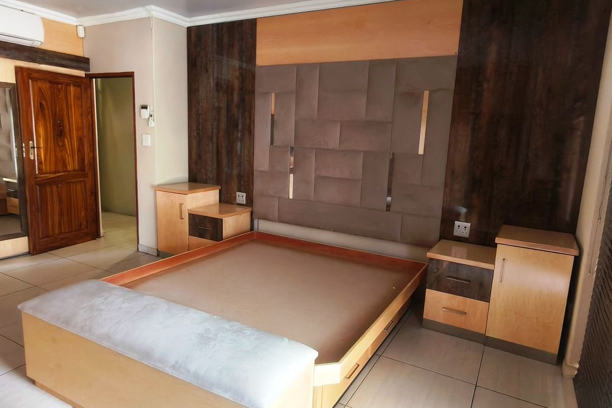 Spacious bedroom featuring built-in cabinetry, a custom headboard with integrated bedside tables, tiled flooring, and an air conditioning unit.