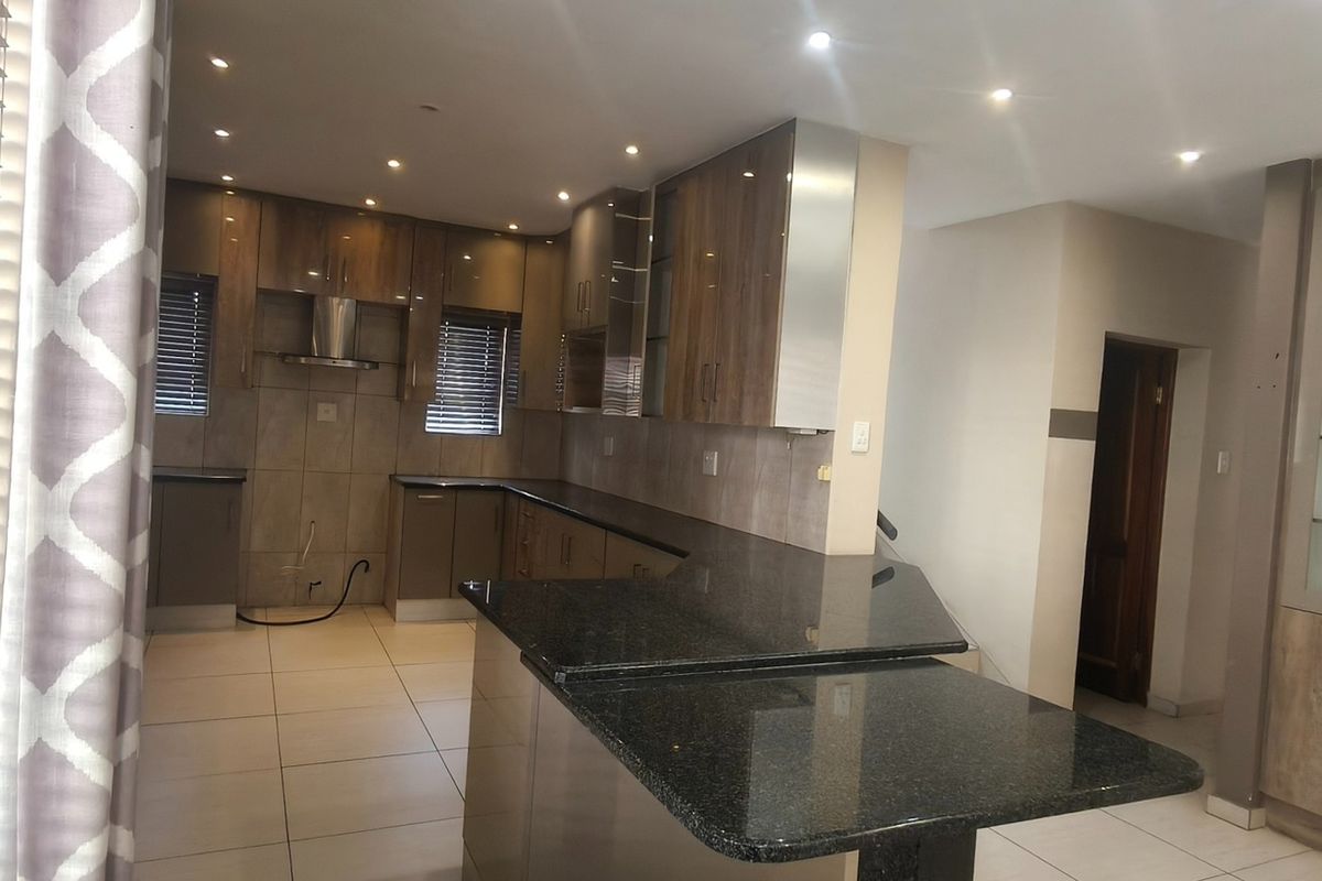 Modern kitchen featuring granite countertops, extensive built-in cabinetry, glass-front display units, and tiled flooring with recessed lighting throughout.