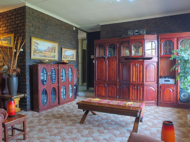 Spacious living room featuring a prominent exposed brick feature wall and traditional carpeted flooring, offering a classic layout with potential for modern updates.
