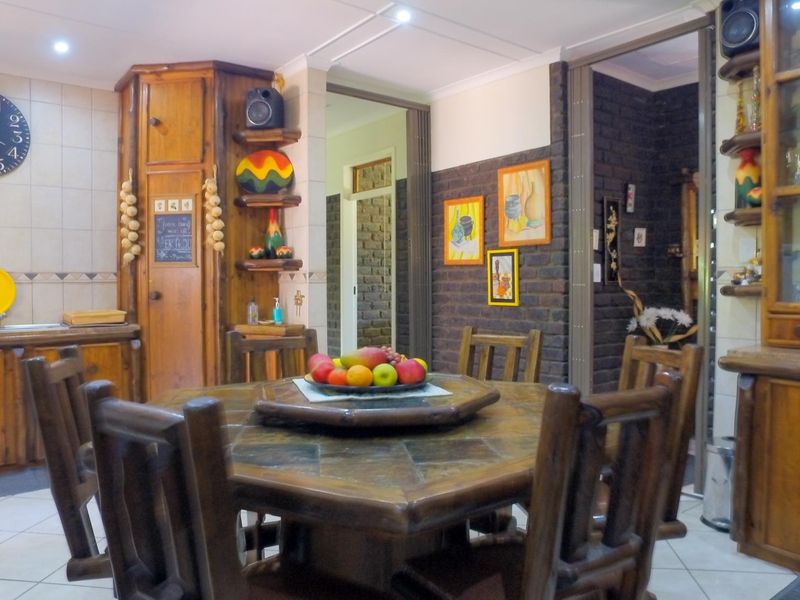 A rustic kitchen featuring extensive built-in wooden cabinetry, tiled flooring, and an exposed brick feature wall, offering a warm and traditional aesthetic.