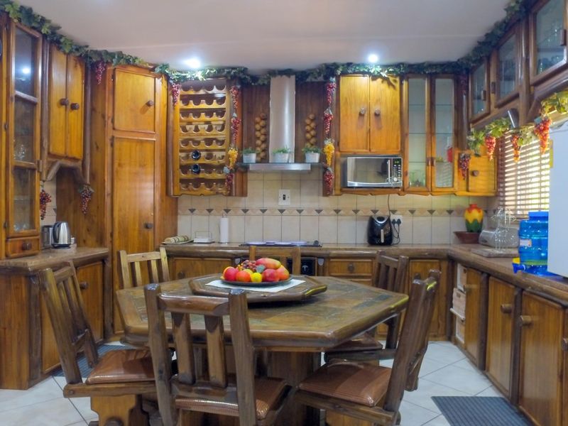 A traditional kitchen featuring extensive wooden cabinetry, a built-in wine rack, tiled backsplash, and integrated appliances, offering a rustic aesthetic.