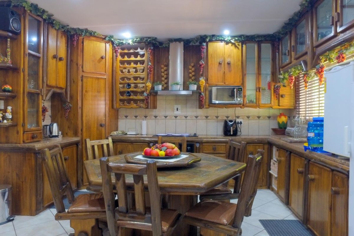 A traditional kitchen featuring extensive wooden cabinetry, a built-in wine rack, tiled backsplash, and integrated appliances, offering a rustic aesthetic.