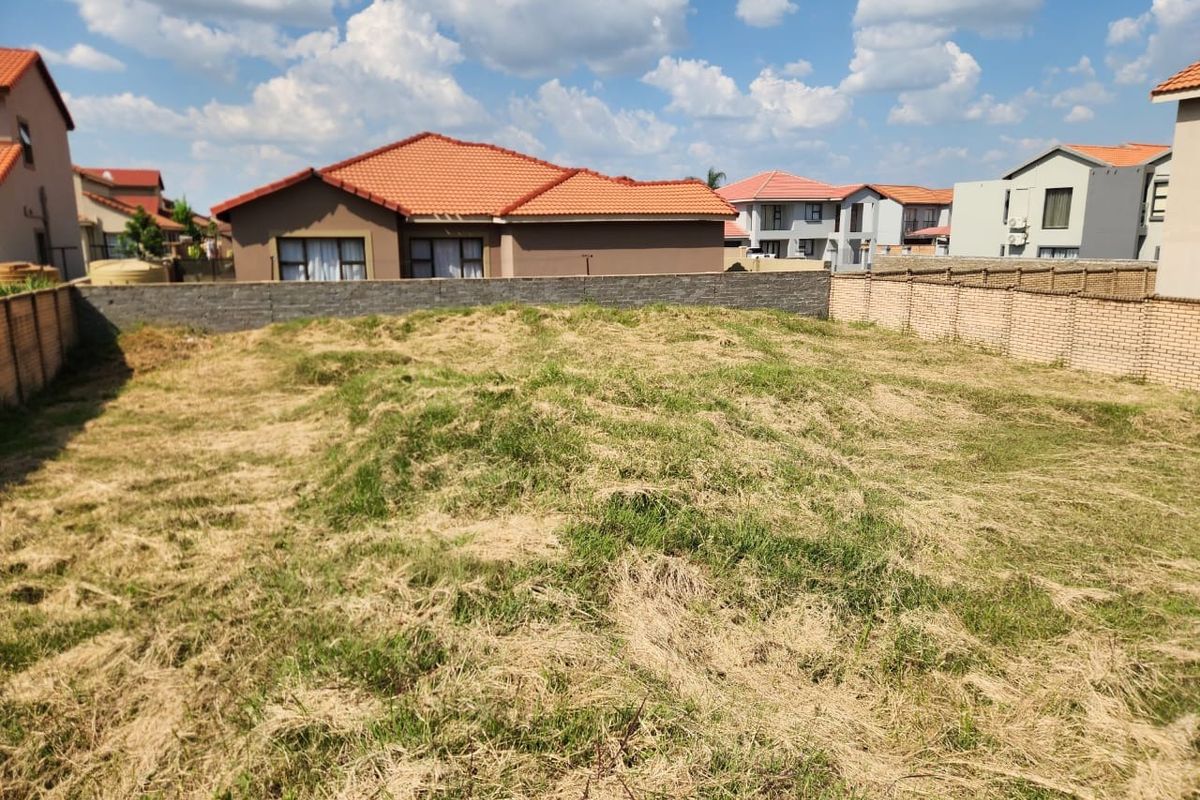 A vacant residential plot featuring perimeter brick boundary walls, situated within an established suburban neighborhood.