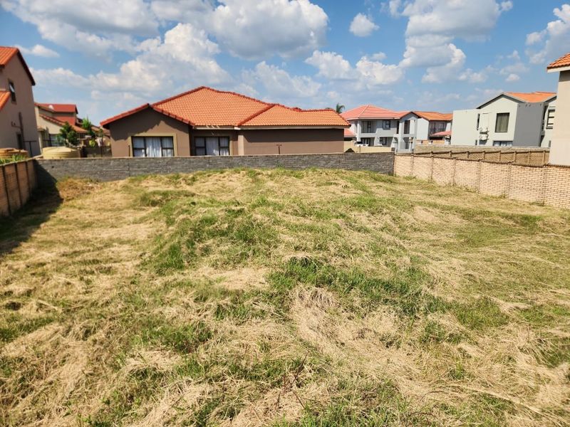 A vacant residential plot featuring perimeter brick boundary walls, situated within an established suburban neighborhood.