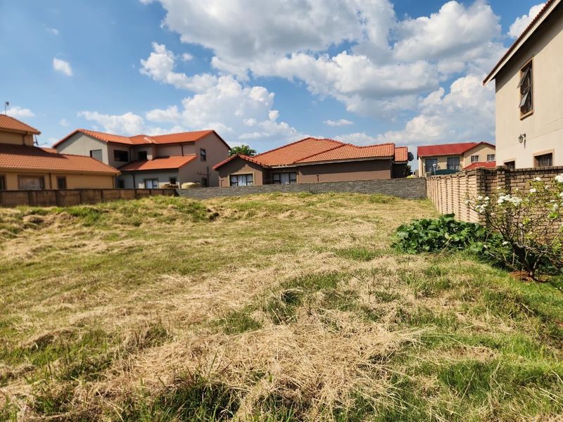 A vacant residential plot featuring established brick boundary walls and surrounding residential development.