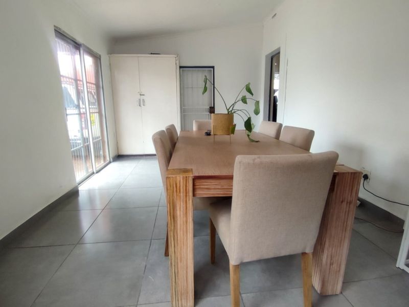 Dining room featuring large format floor tiles, a sliding glass door for natural light, and a built-in storage cupboard.