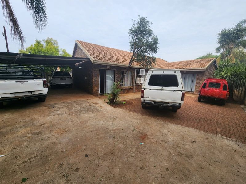 Front exterior view of a brick house featuring a tiled roof, paved driveway, and a covered carport area.