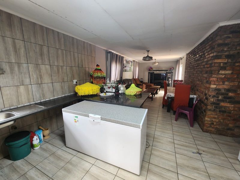 Open-plan living and kitchen area featuring tiled floors, an exposed brick feature wall, granite countertops, and a functional kitchen workspace.