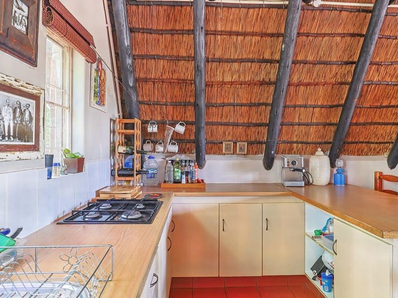 Kitchen featuring a unique thatched ceiling with exposed timber rafters, gas hob, laminate countertops, and built-in cabinetry.