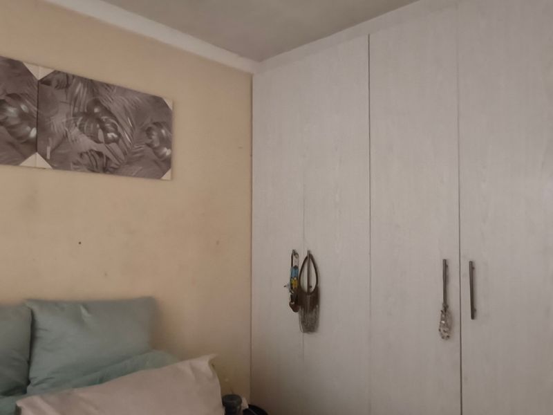 A bedroom featuring built-in cupboards with white wood-grain finish doors and neutral wall tones.
