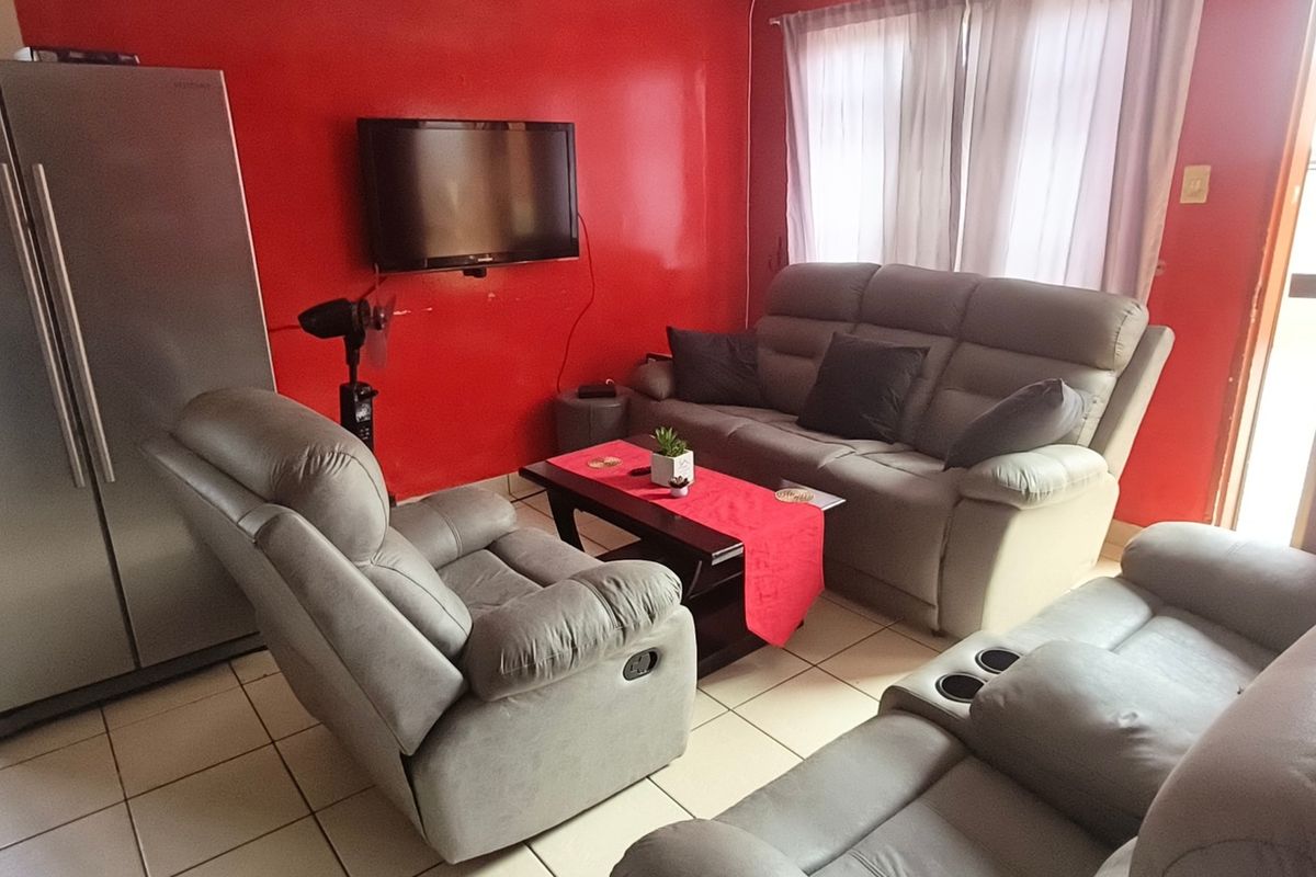 A living room area featuring tiled flooring and a bold red accent wall.