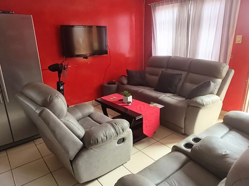 A living room area featuring tiled flooring and a bold red accent wall.