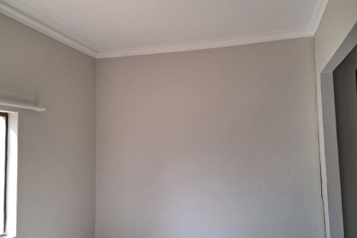 A clean, empty bedroom featuring neutral wall paint, crown molding, and tiled flooring, providing a blank canvas for personalization.