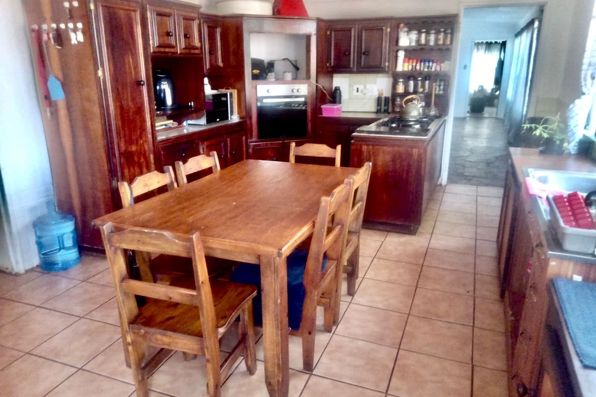 Open-plan kitchen and dining area featuring traditional wooden cabinetry, built-in oven, gas hob, and ceramic floor tiles.