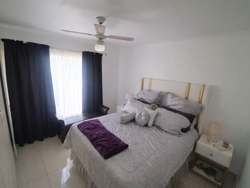 A well-maintained bedroom featuring tiled flooring, a ceiling fan, and built-in cupboards, offering a clean and functional living space.