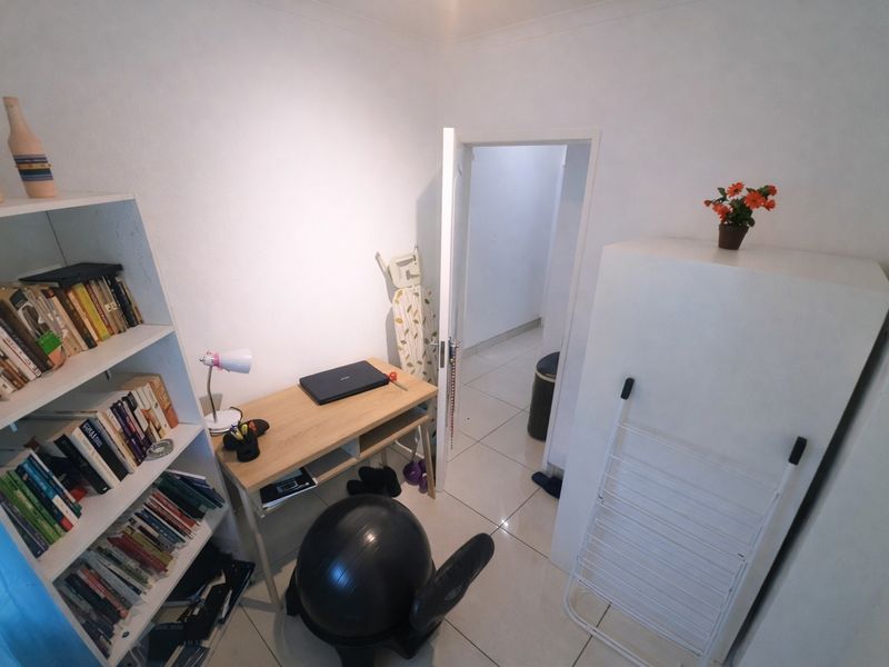 A functional home office space featuring tiled flooring and neutral wall finishes, providing a versatile area for work or study.
