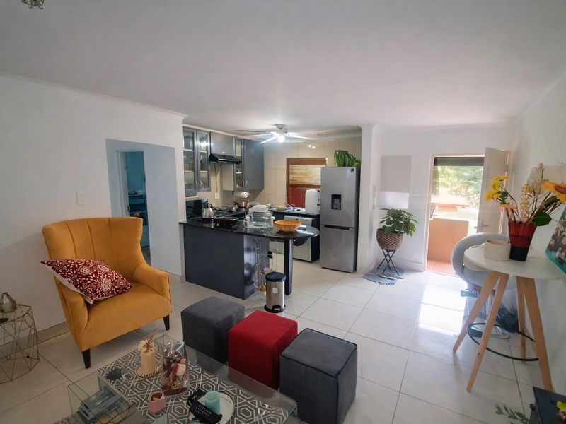 Open plan living area featuring a modern kitchen with granite countertops, tiled flooring throughout, and direct access to an outdoor balcony.