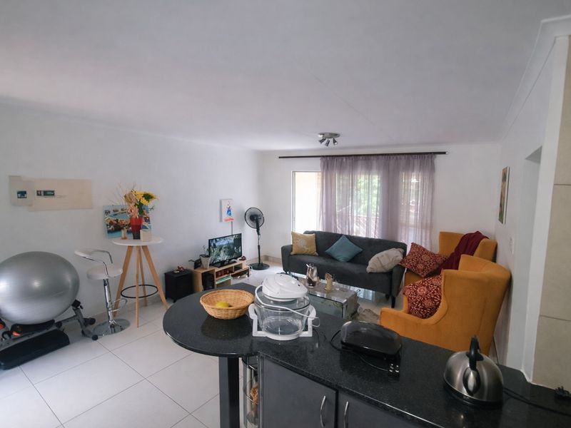 Open-plan living area featuring tiled floors and a kitchen with granite countertops, providing a functional and connected space for daily living.