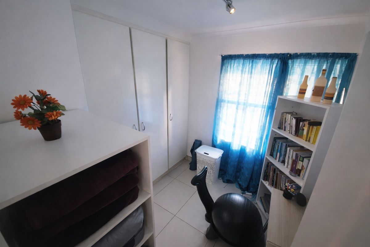 A compact bedroom featuring tiled flooring and white built-in cupboards, offering functional storage space.